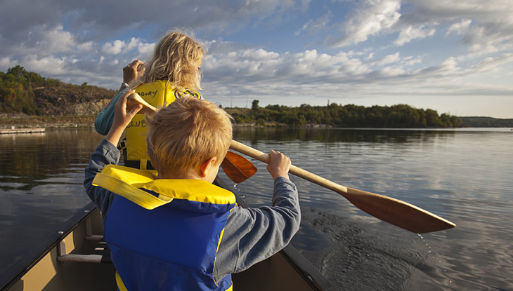 A woman and young son paddling in a canoe on a summer day in Northern Ontario.