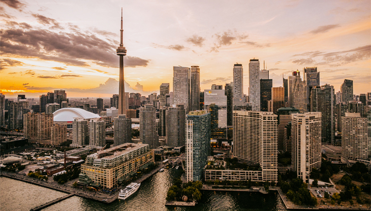 Cityscape view of Toronto from the harbour with the CN Tower and downtown standing against a dramatic sky.