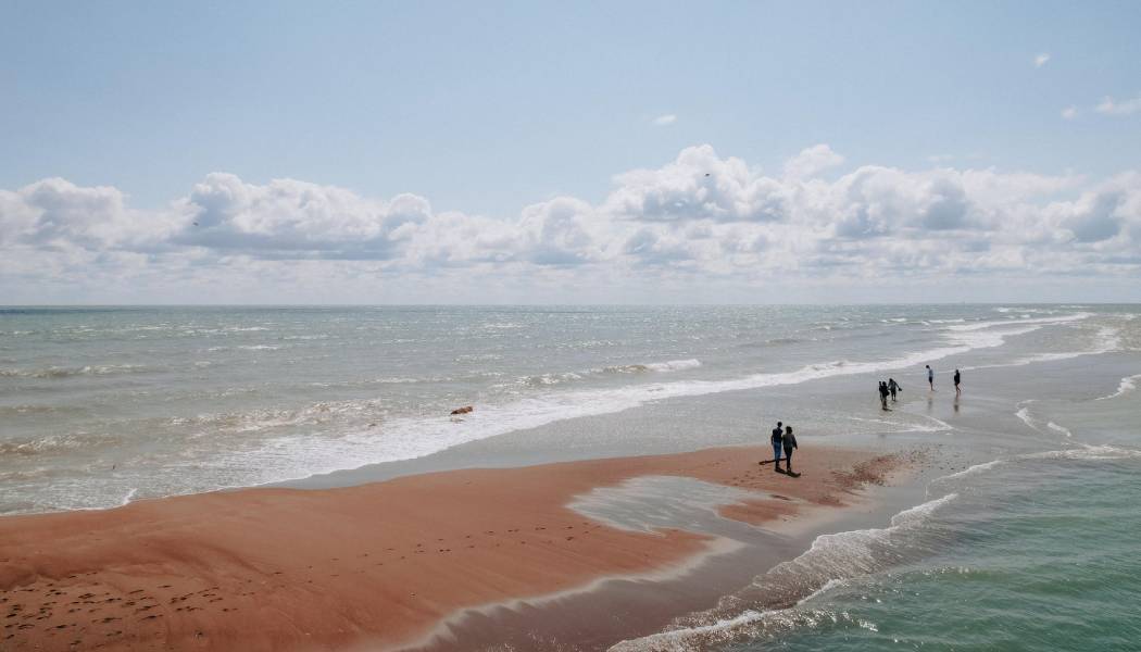 エリー湖を見下ろすビーチの砂州で、男性が女性をブランコに乗せている。