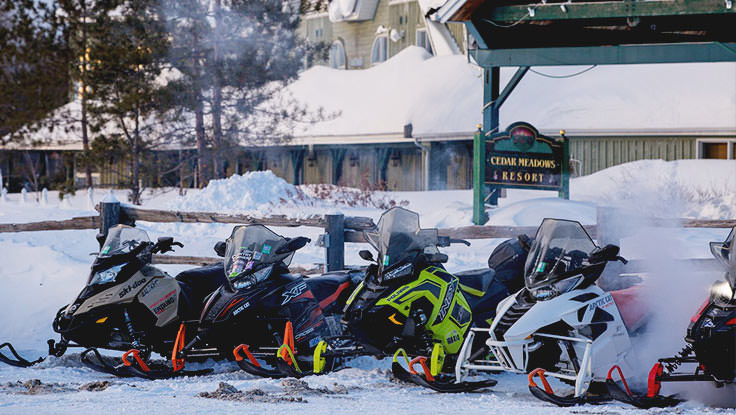Eine Reihe von Schneemobilen, die vor einem Resort geparkt sind