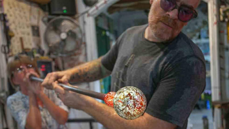 Two artists creating glass blown artwork.