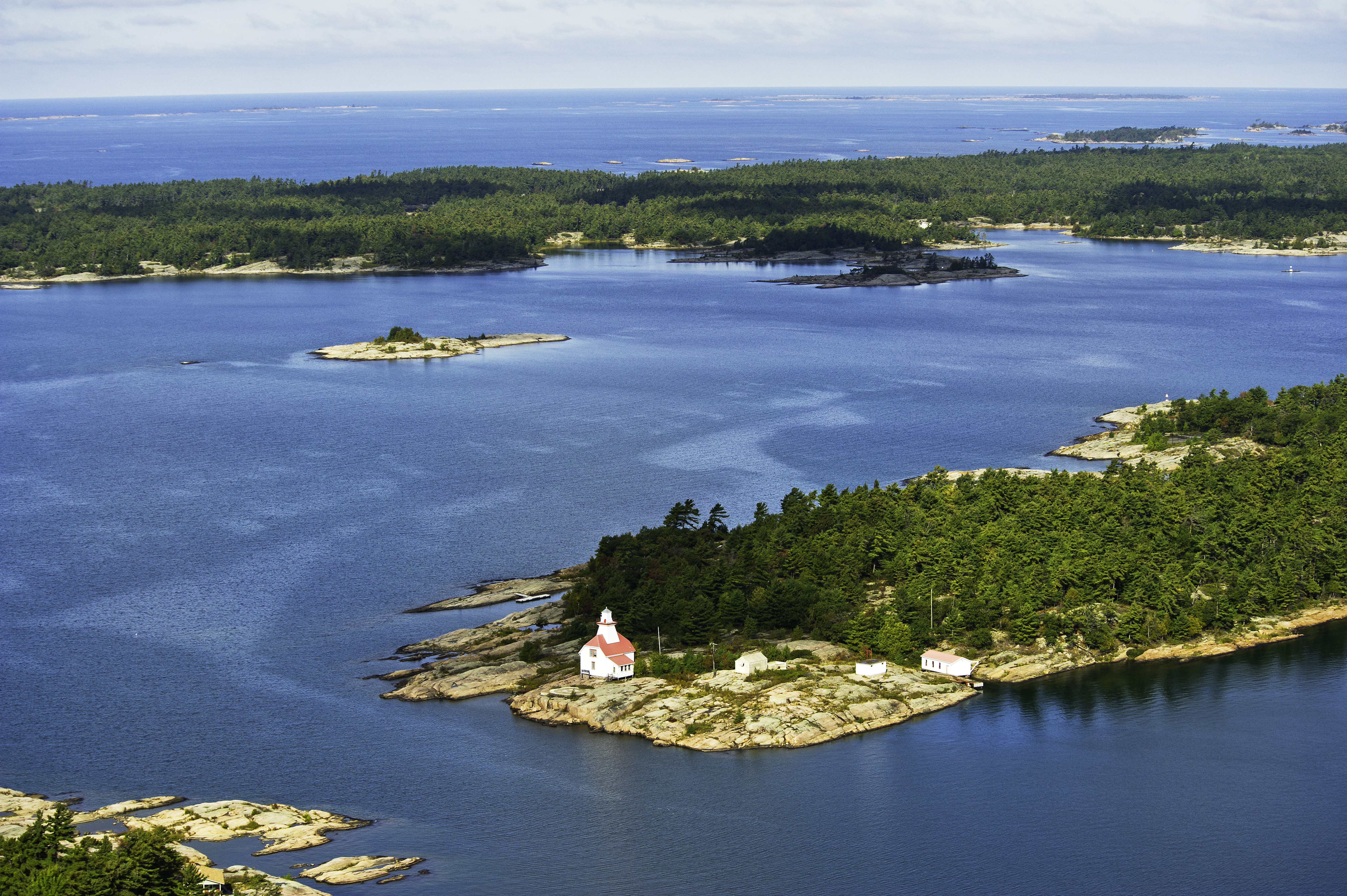A lighthouse sits on a peninsula overlooking a lake.