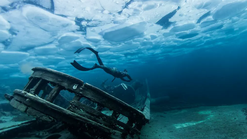 Eine Person taucht um ein Unterwasserwrack in Ontario herum.