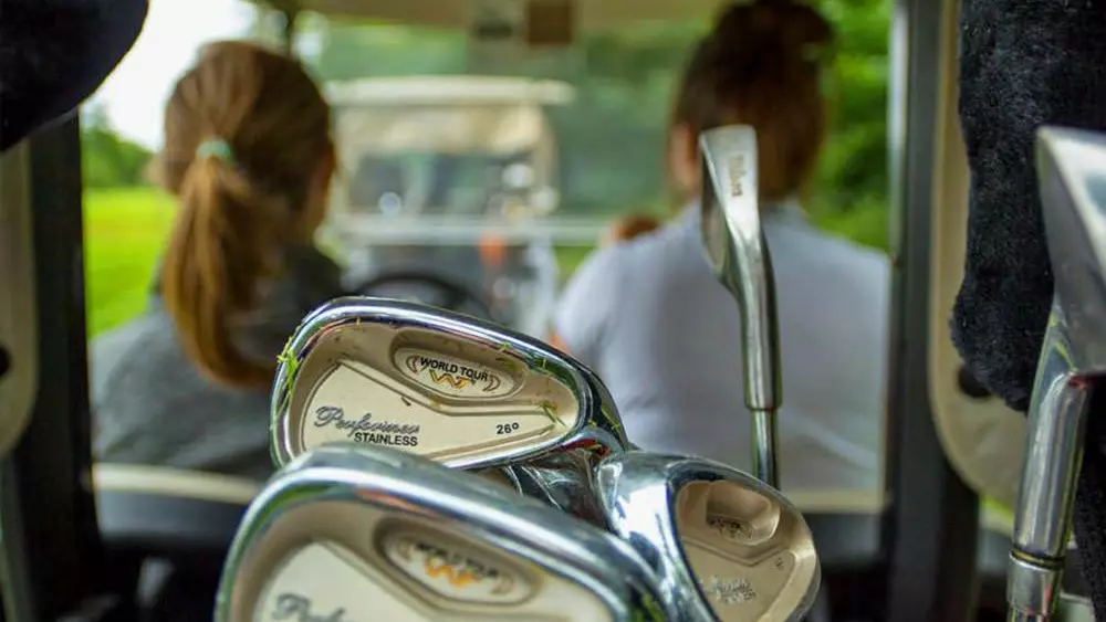 두 여성이 온타리오 골프장을 가로질러 골프카트를 운전하고 있습니다.