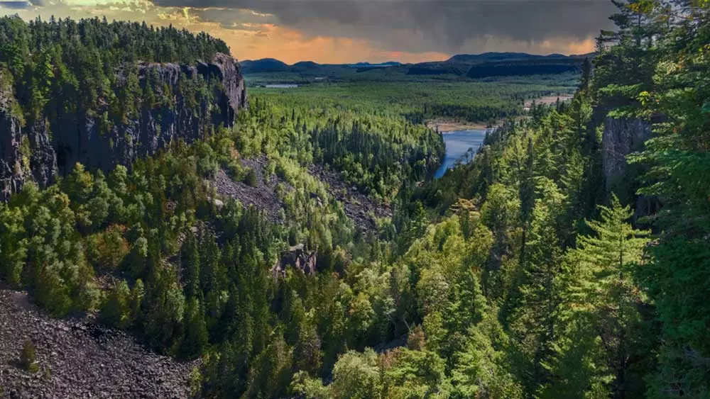 Ein weitreichender Blick auf den Ouimet Canyon mit Wald und Seen im Hintergrund.