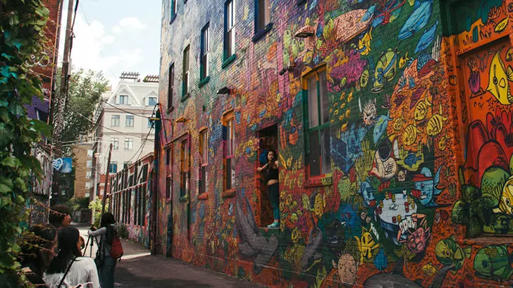 A group of people walking down Graffiti Alley in Toronto.