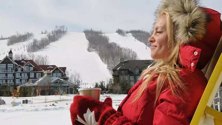 다운힐 스키를 한 후 따뜻한 음료를 마시며 휴식을 취하고 있는 여성.