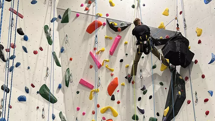 A man climbs a wall in an indoor rock climbing facility.
