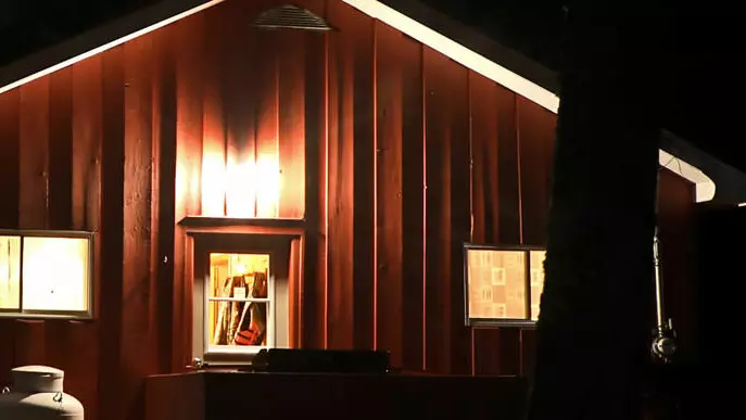 ライトは、素朴な木製の狩猟小屋の側面を照らします。