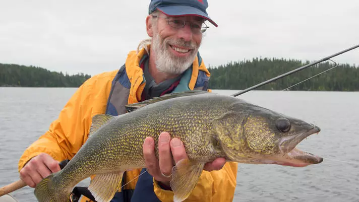 Ein Mann hält einen großen Fisch hoch, der bei einem Angelturnier gefangen wurde.
