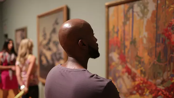 People admiring art on a wall in a gallery.