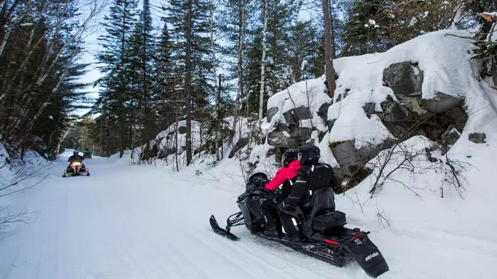 Schneemobilfahrer fahren in verschiedene Richtungen entlang eines befestigten Pfades.