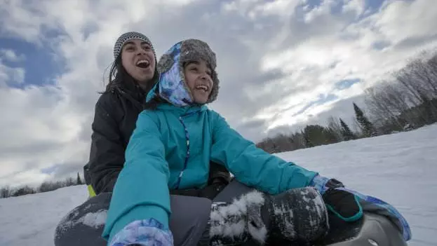 Two smiling people riding in a toboggan
