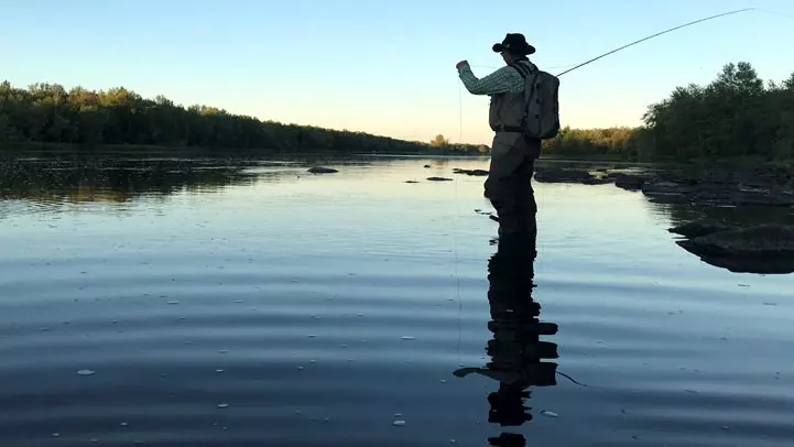夕暮れ時にグランド川でフライフィッシングをする男性。