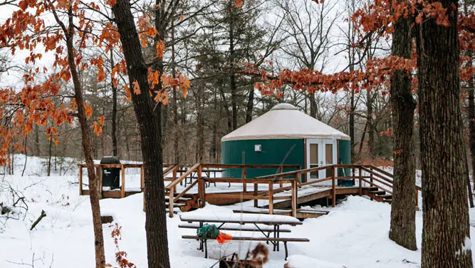 A small, round yurt in the forest during winter in Pinery Provincial Park.