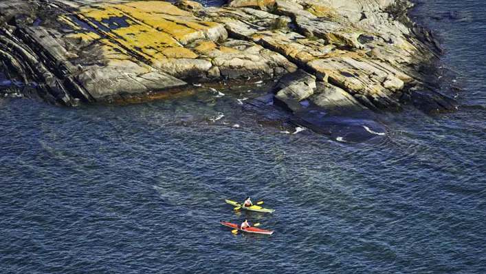 Zwei Personen fahren mit dem Kajak an einem großen Felsen in der Georgian Bay vorbei.