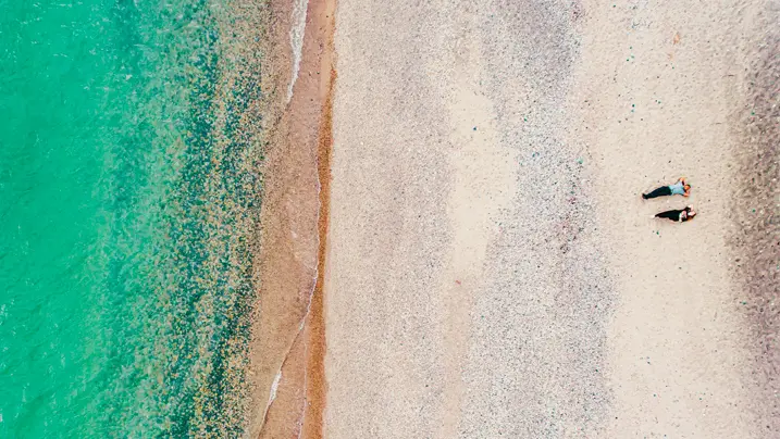 Vue aérienne de deux personnes allongées sur une plage de sable blanc du lac Huron.
