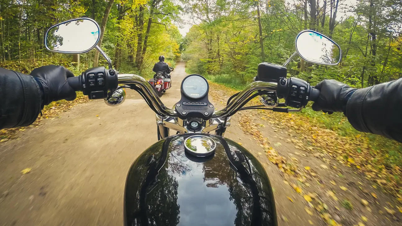 Two people are riding motorcycles on a trail.