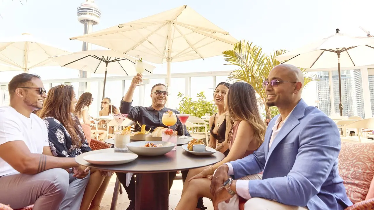 Un grupo de amigos sentados en una mesa tomando bebidas y bocadillos.