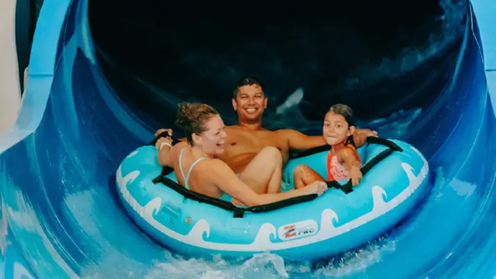 屋内ウォーターパークのウォータースライダーを楽しむ家族