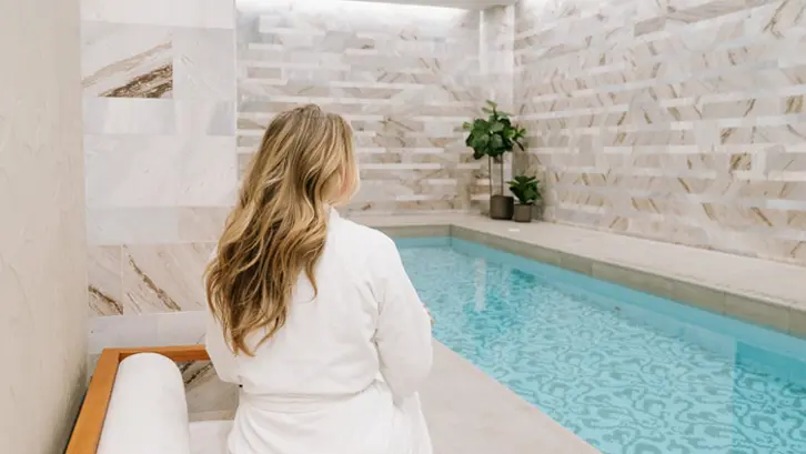 心地よいテリー織りのローブを着た女性が、トロントのヘーゼルトン ホテルのスパ プールの横に座っている。