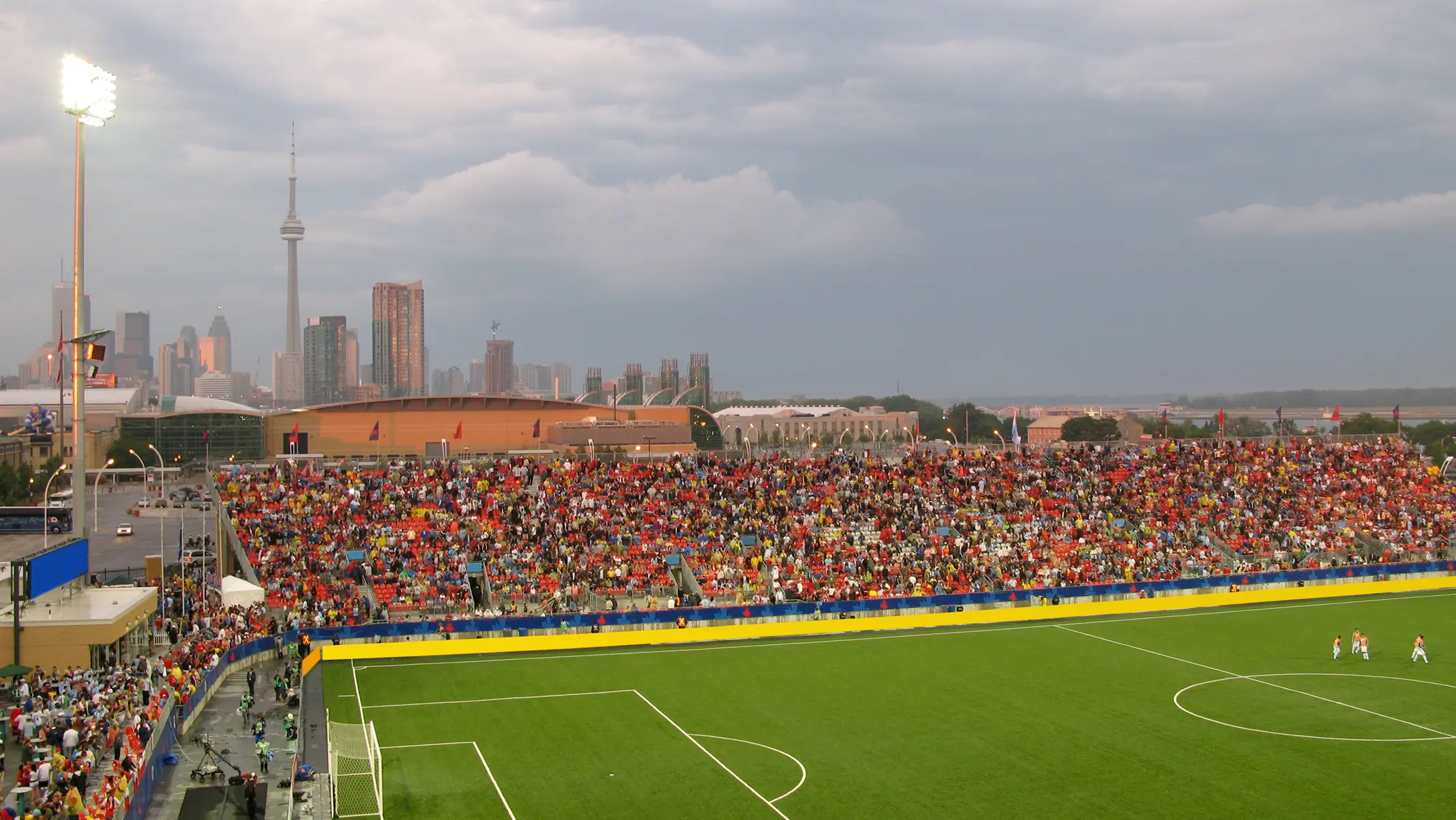 Un cielo oscuro y nublado se cierne sobre un campo de fútbol con gente sentada en las gradas.