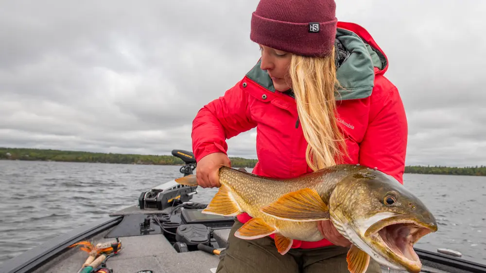 A woman holds a fish in preparation to release it back to the lake.