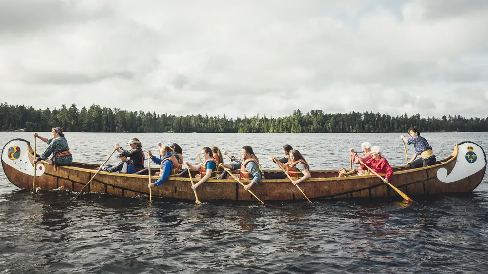 ケティコ公園にある歴史的なボヤージャーカヌーの複製で漕ぐ人々のグループ。