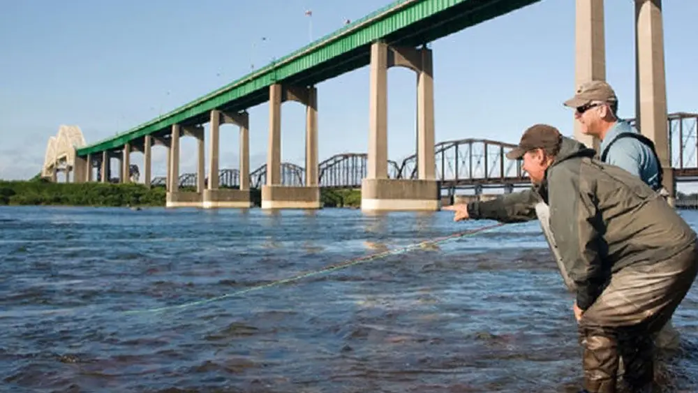 Dos hombres pescando deportivamente en el río St. Mary's en Sault St. Marie, Ontario.