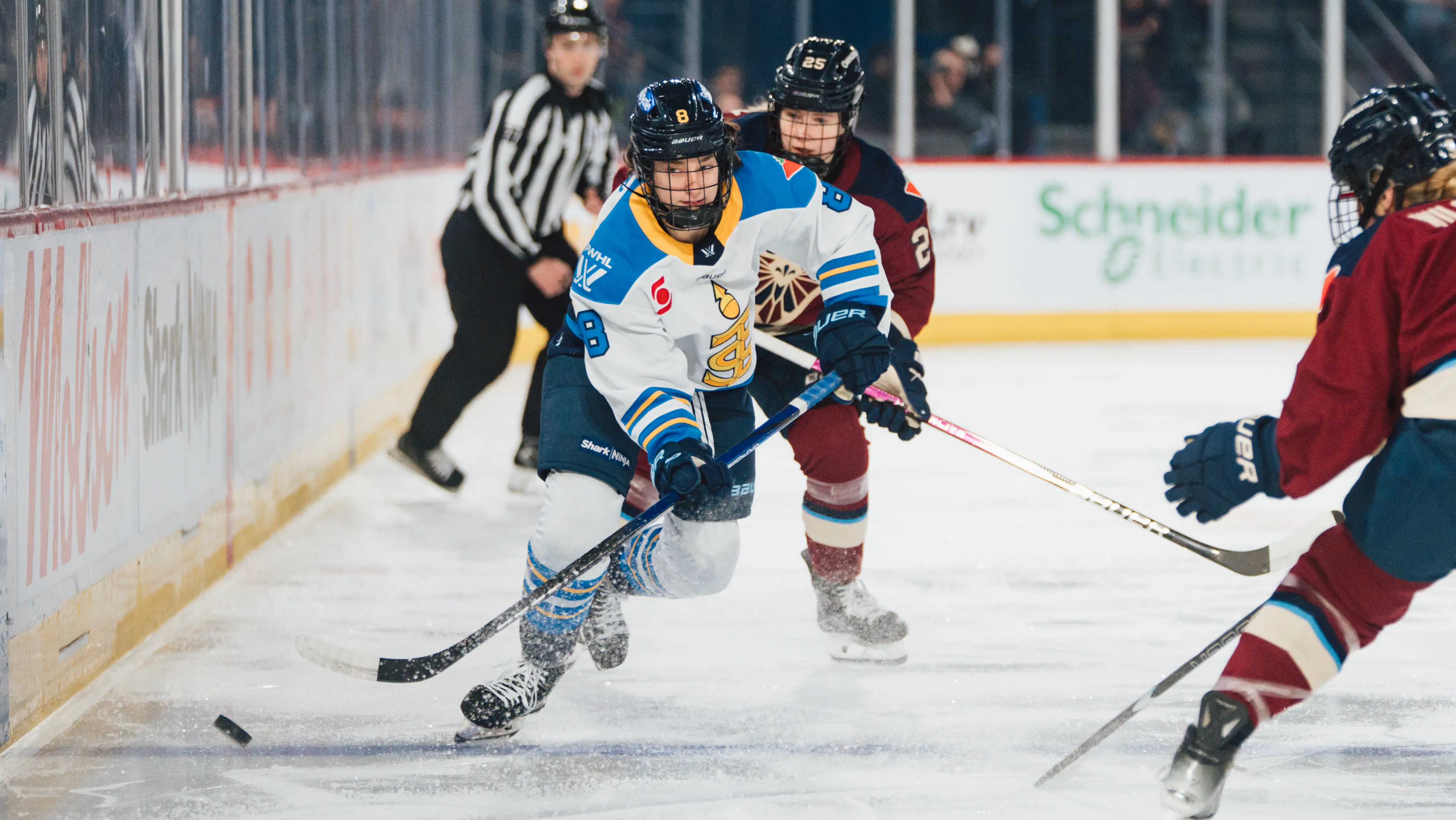 Joueuse des Sceptres de Toronto affrontant deux femmes de l’équipe adverse dans un match de hockey.