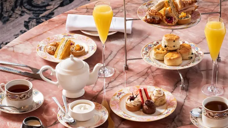 Ein High Tea mit Süßigkeiten, herzhaften Leckereien und Mimosen wird auf einem rosa Marmortisch im Zoe's im Fairmont Château Laurier in Ottawa serviert.