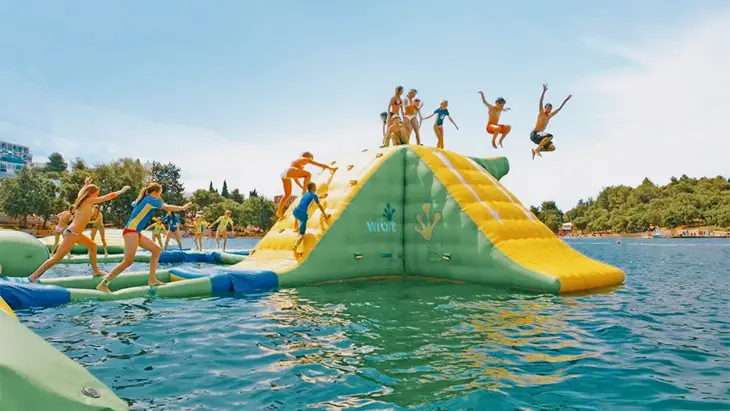 スプラッシュタウン マニトゥリンの浮きアクションタワーに登ったり、透き通った青い水に飛び込んだりする子供たち。