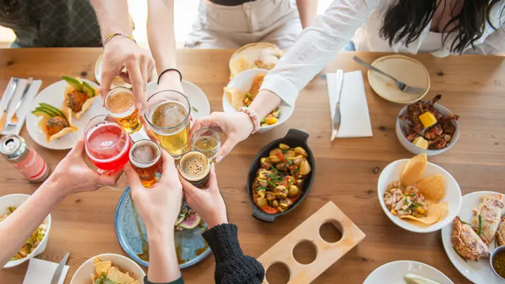 파슨스 브루잉에서 사람들이 애피타이저와 나눠 먹을 수 있는 접시 위에 다양한 음료로 건배하고 있습니다.