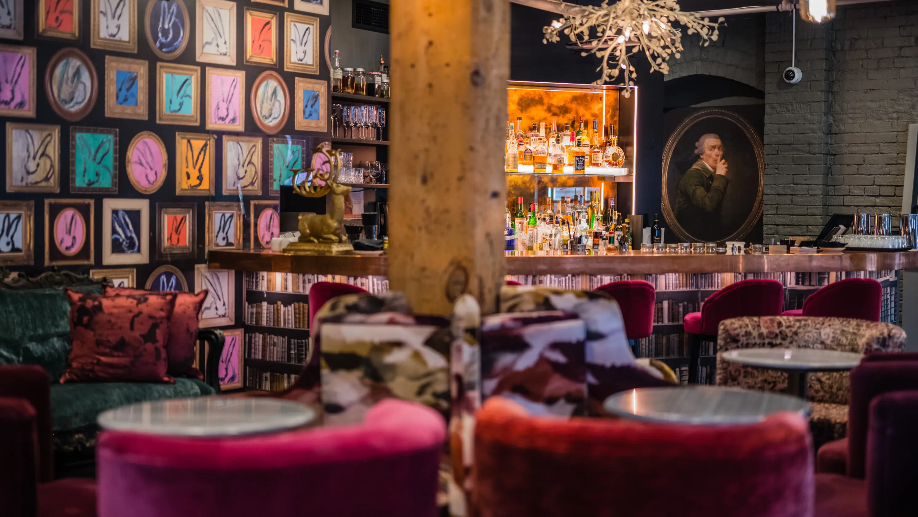 Interior of Secrette, a hidden bar in Toronto, featuring velvet chairs, eclectic art and a cozy, colourful ambiance.