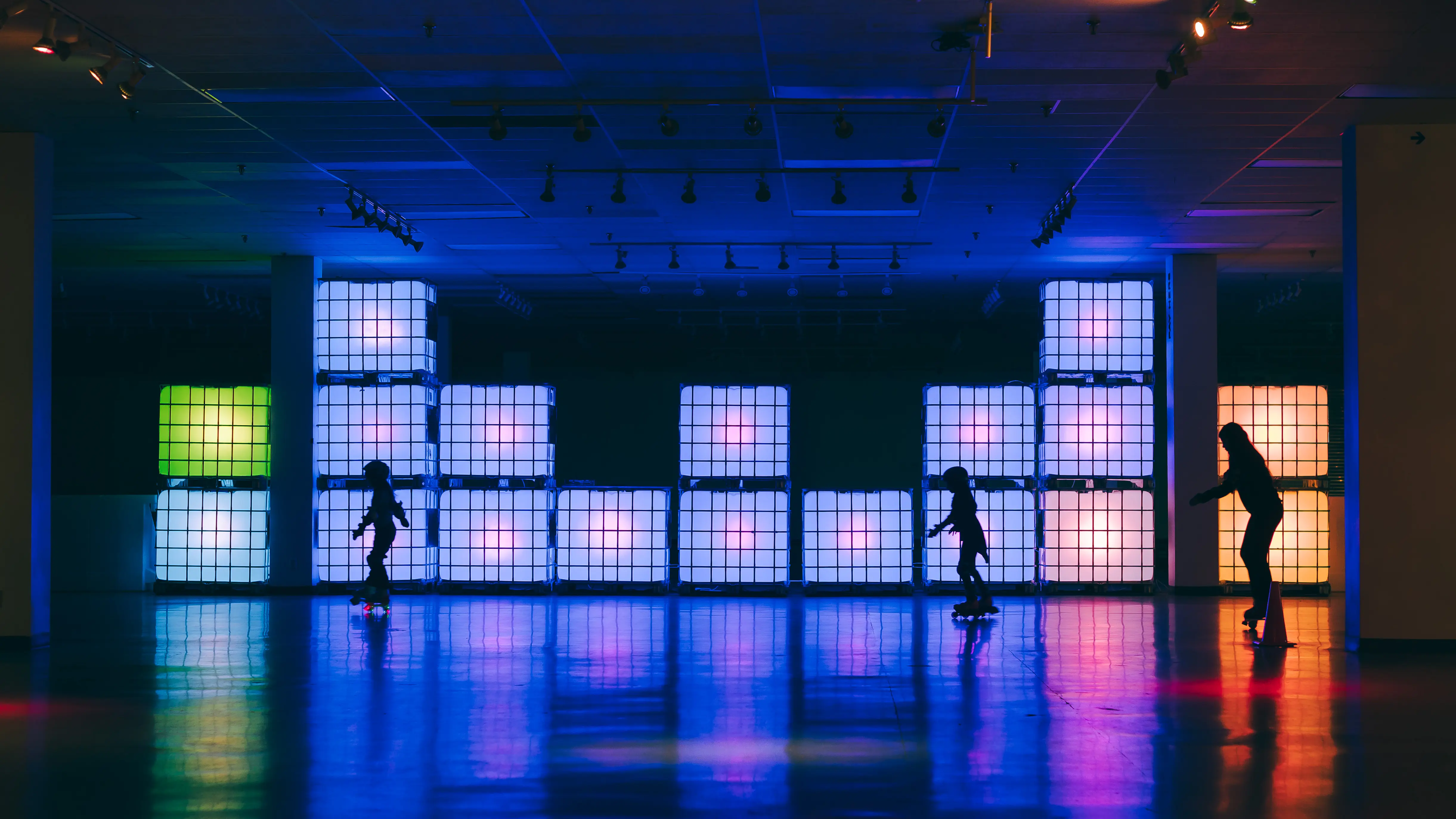 Tres niños patinando frente a bloques coloridos que brillan.