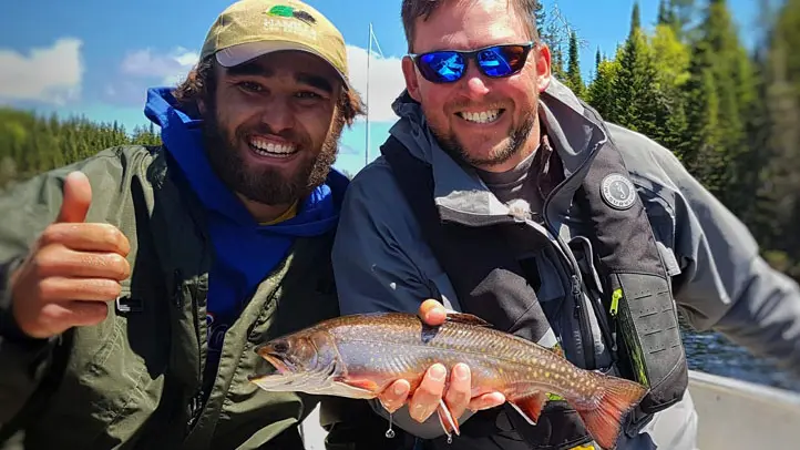 Ein erfolgreicher Angler posiert mit seinem Angelguide, der einen Fisch hält.