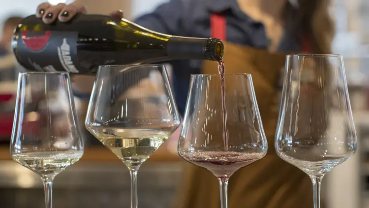 Una persona vierte vino tinto en una copa para una degustación en Adamo Estate Winery.