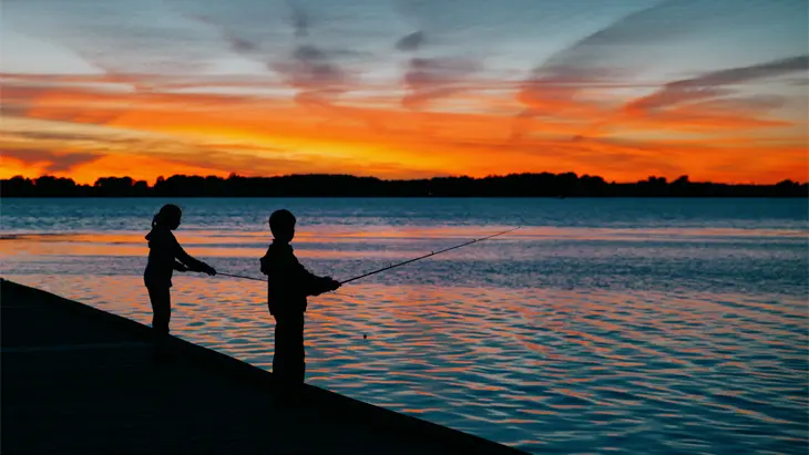 Zwei Personen angeln bei Sonnenuntergang auf einem Steg am Eriesee in Leamington.