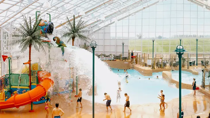 Indoor water park featuring a water slide and kids' splash zone with a giant tipping bucket at Americana Resort in Niagara Falls.