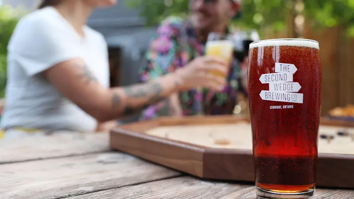 Deux personnes dégustent une bière artisanale sur une terrasse extérieure de la brasserie Second Wedge à Uxbridge.