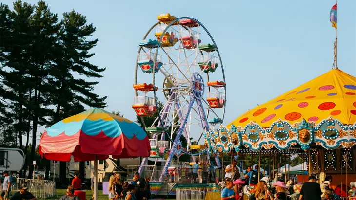 The busy Spencerville Fairgrounds with a yellow carousel on the right and a Ferris wheel pictured centred.