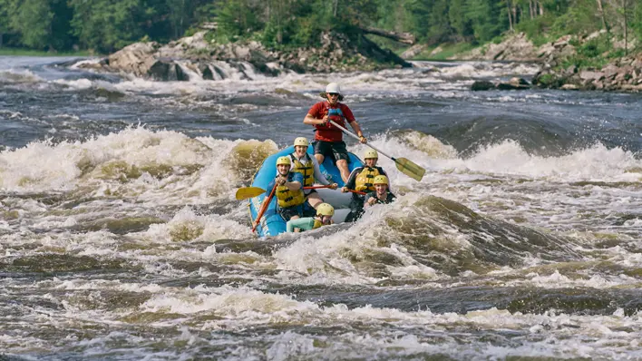 A group of people whitewater rafting on the Ottawa River with Wilderness Tours guides.