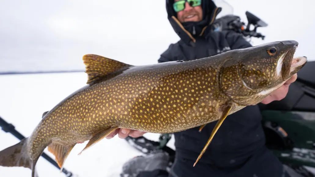 A man ice fishing at Browns Clearwater West Lodge holds up a large catch.