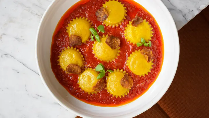 A bowl of vegetarian ravioli in tomato sauce served at Gia, a MICHELIN recognized restaurant in Toronto.