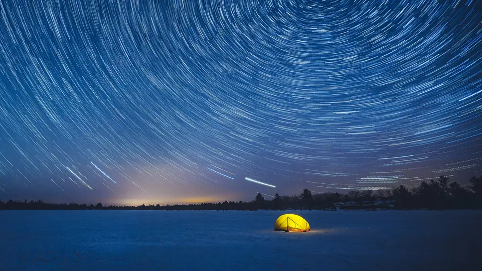 マスコカのトーランス・バレンズの雪の夜景に立つ黄色いテントが、星空のまばゆい光に照らされています。