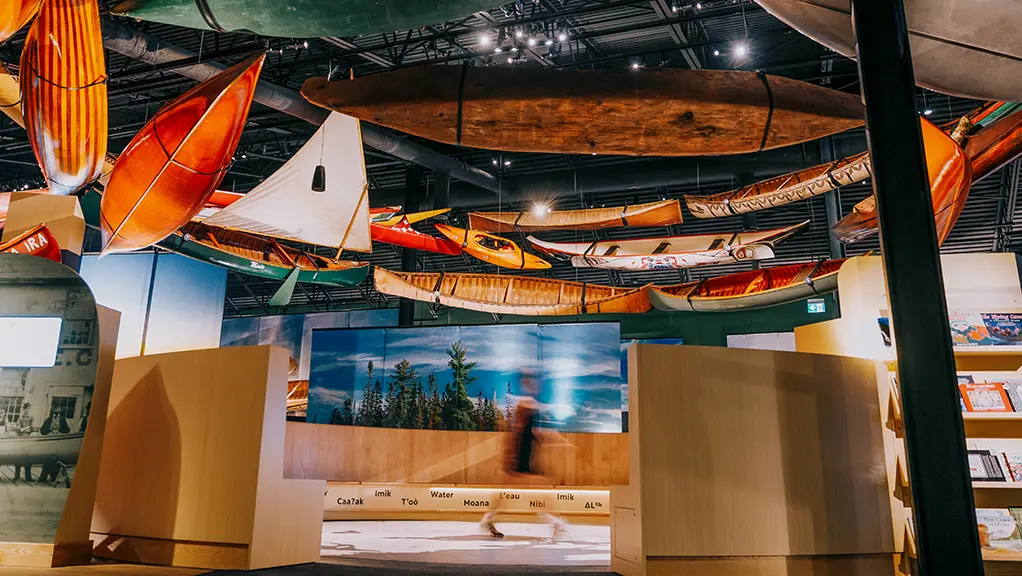박물관 갤러리에는 전시물 위 천장에 카누와 카약이 매달려 있습니다.