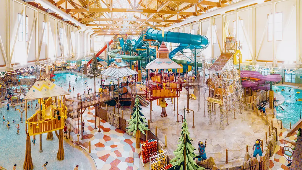 A colourful indoor waterpark with splash zone, pool area and water slides.