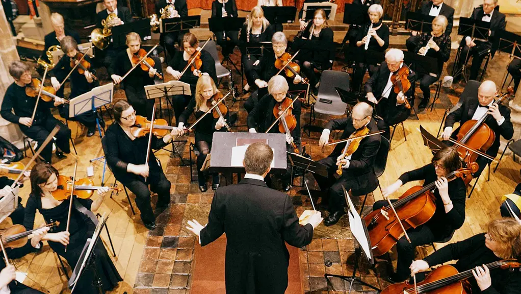 Orquesta actuando con un director durante un concierto en vivo.