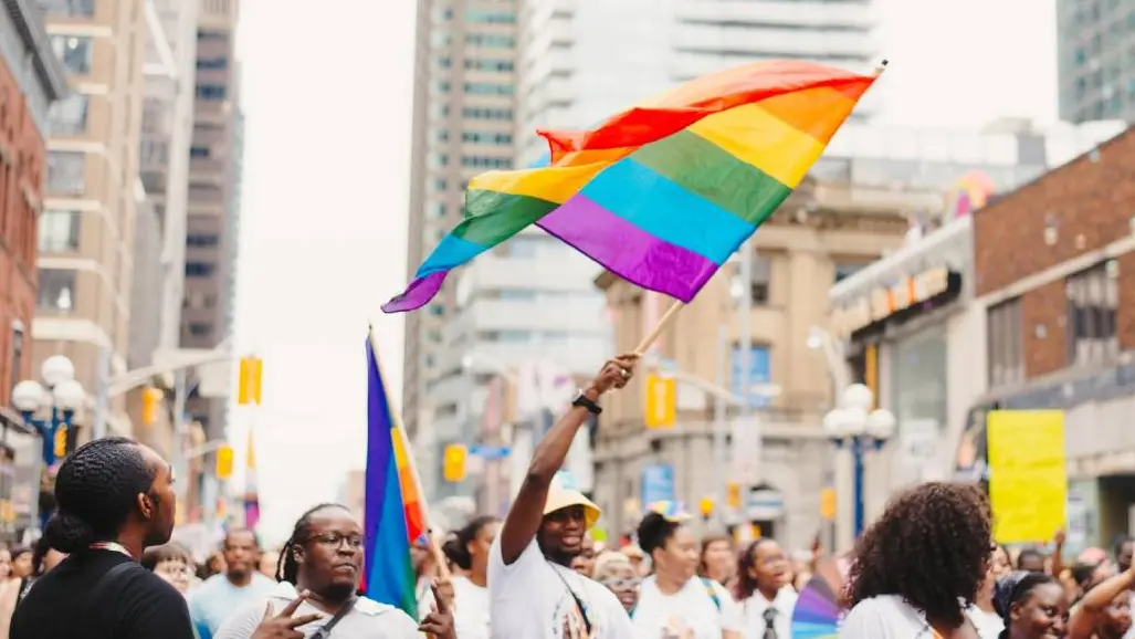 한 남성이 토론토 시내에서 프라이드 행사를 기념하는 행렬에 참여하며 무지개 깃발을 흔들고 있습니다.