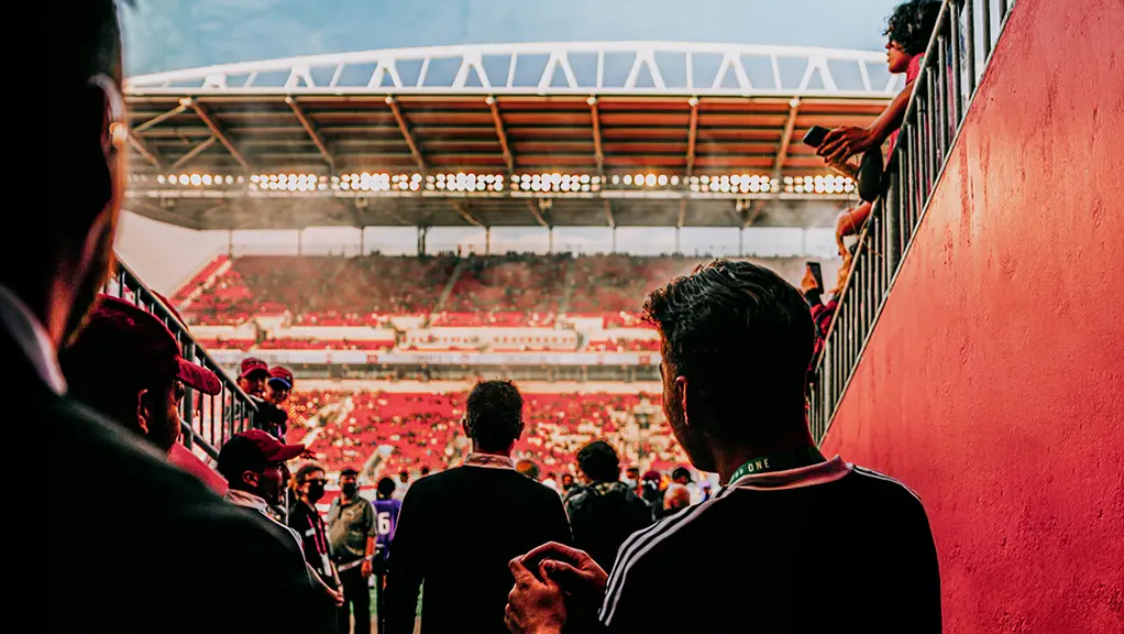 Jugadores de fútbol caminando por un túnel del estadio hacia el terreno de juego antes de un partido.